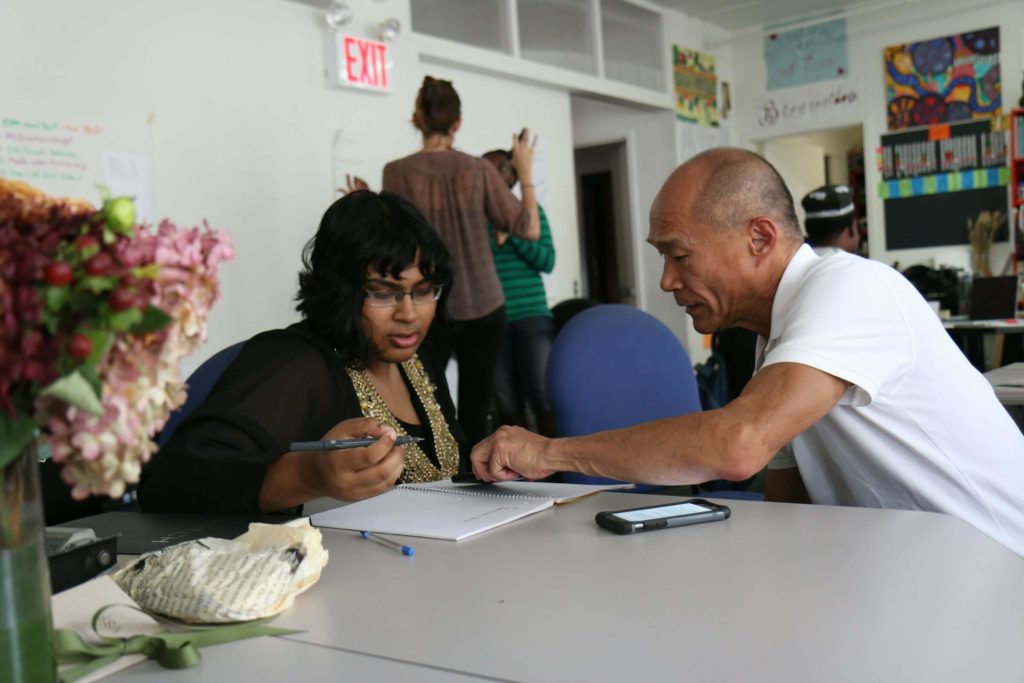 A middle aged man helping a young woman with paperwork